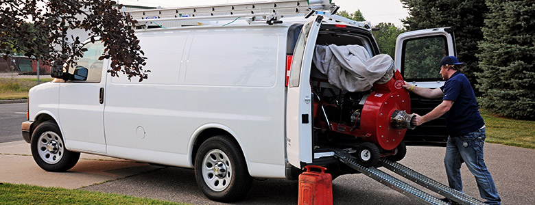 and air duct cleaning tech removing equipment from the back of a white van.